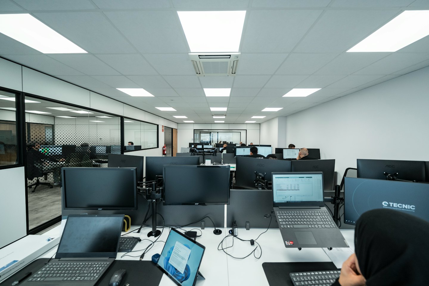 Menschen arbeiten an Computern in einem modernen Großraumbüro.