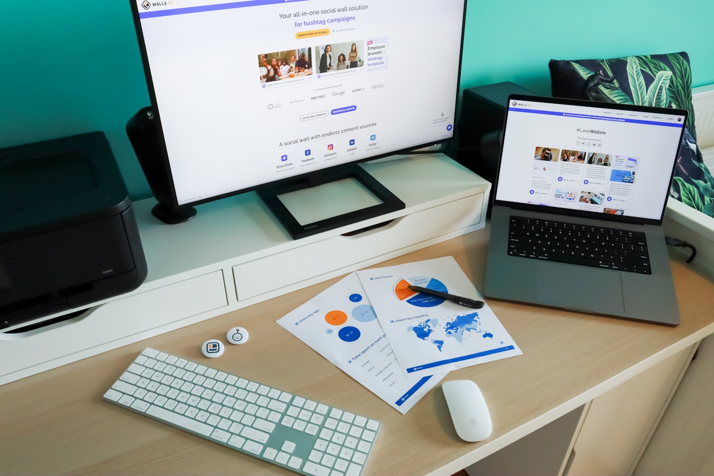 Schreibtisch im Homeoffice mit Monitoren, Berichten und Drucker.